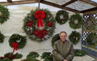 person standing in front of shop display of christmas wreaths