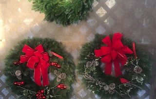 three christmas wreaths on display with bows
