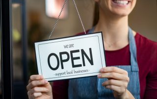 Woman holding a "We Are Open" sign.