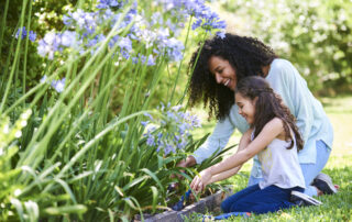 mother and daughter spring gardening together with purple flowers